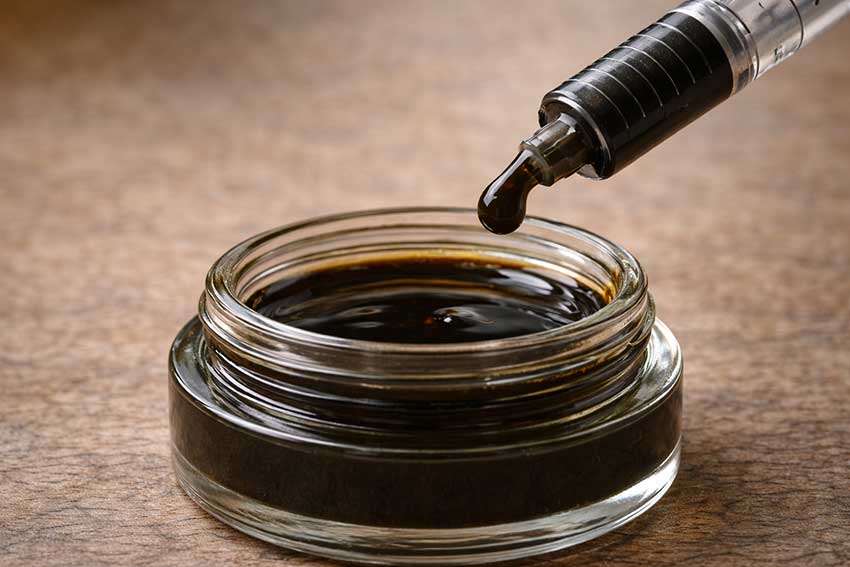 RSO Rick Simpson Oil dark cannabis extract being dispensed from a syringe at Huff and Puff Dispensary