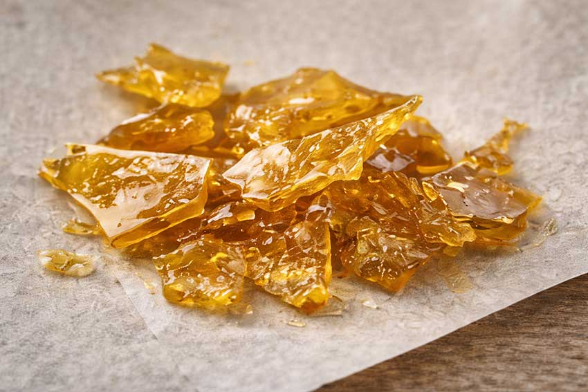 Translucent golden cannabis shatter on parchment paper at Huff and Puff Dispensary